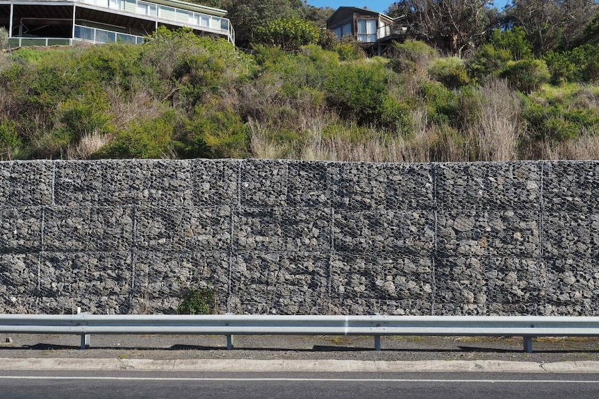 A 2m high wall made from grey rocks and held together with wire runs along a section of the hills beside the Great Ocean Road.
