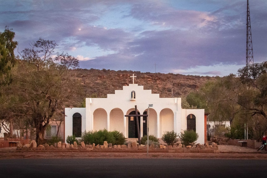 A white church stands against the arid landscape of Central Australia.