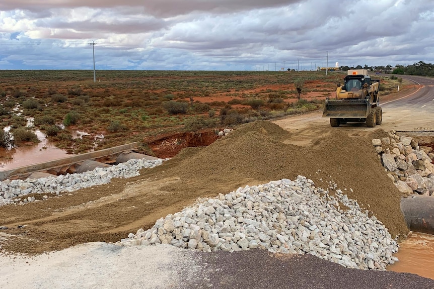 Rubble and rocks being put onto a desert highway by a bobcat