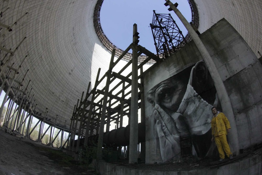Street artist Guido van Helton with mural in Chernobyl Reactor 5