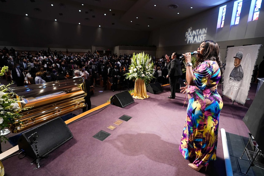 A singer performs by the casket of George Floyd during a funeral service for Floyd at The Fountain of Praise church