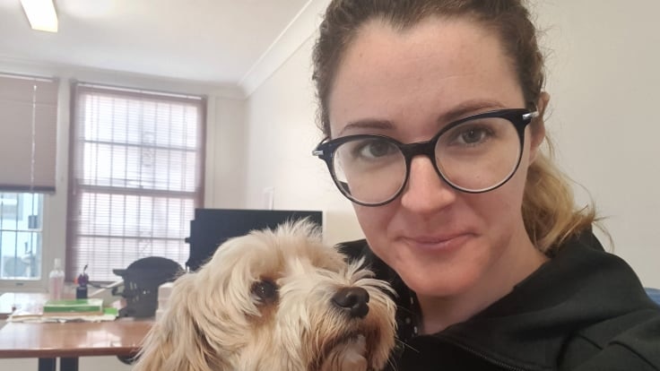 Ilina Lovely is pictured with her dog in her home, wearing glasses