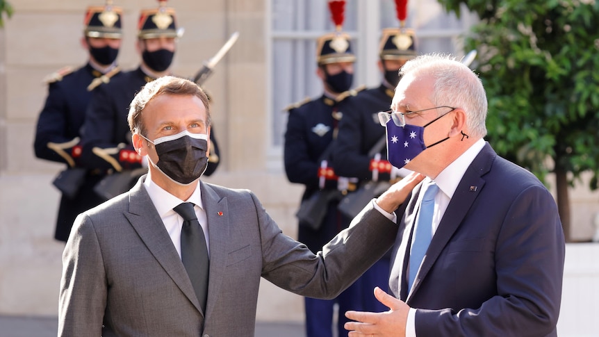 French President Emmanuel Macron puts his hand on the shoulder of Australian Prime Minister Scott Morrison