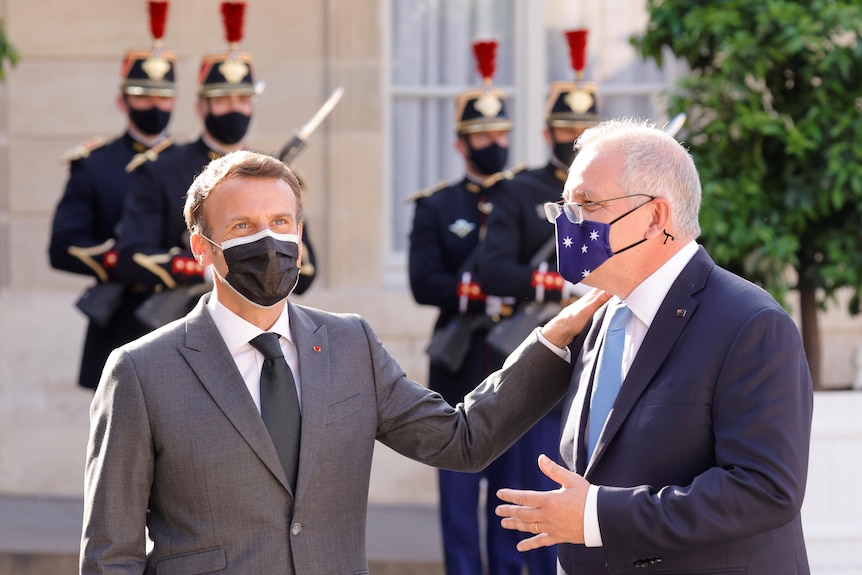 French President Emmanuel Macron puts his hand on the shoulder of Australian Prime Minister Scott Morrison