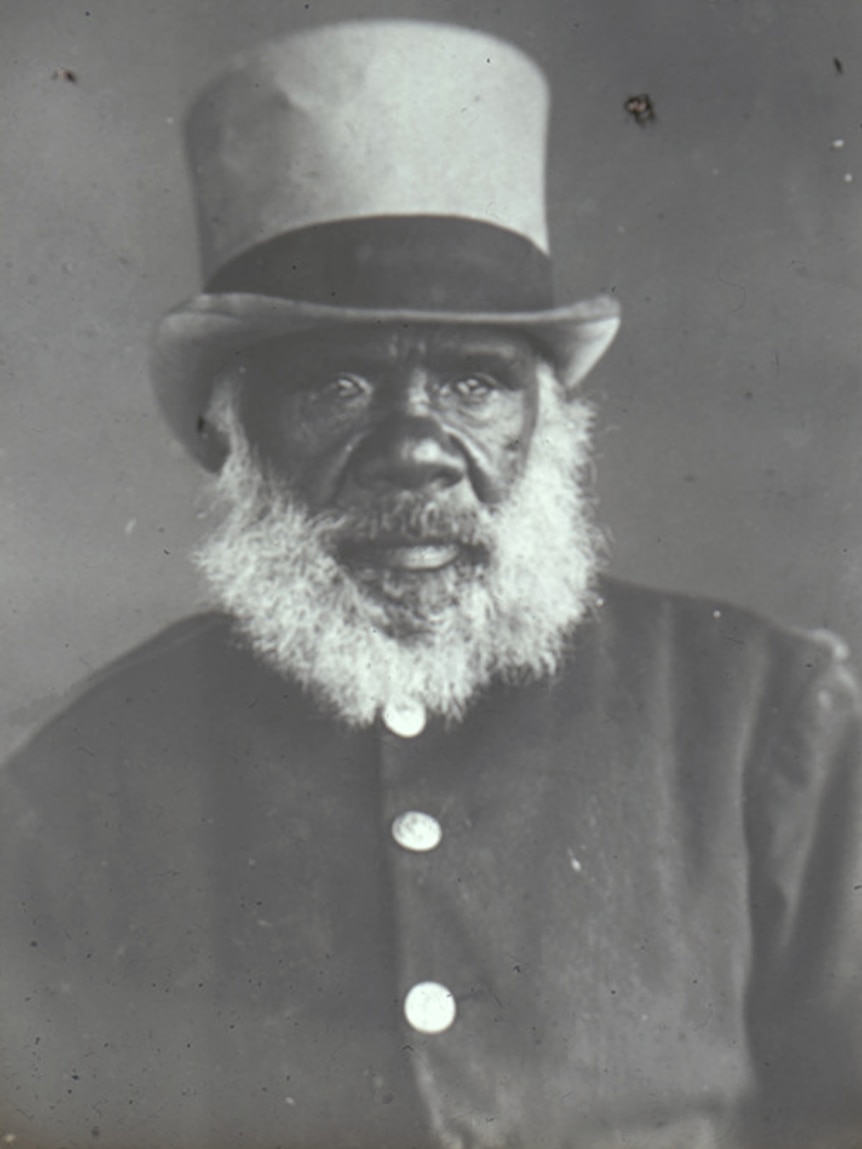 Black and white photo of an Indigenous man with a bushy beard and top hat.