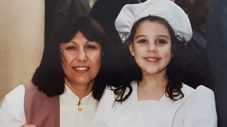 An old film photo of Danielle Snelling and mum (Rosa); they wear white and smile to the camera.