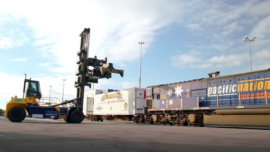 Train cars are loaded by a machine for their journey from Perth to Brisbane.