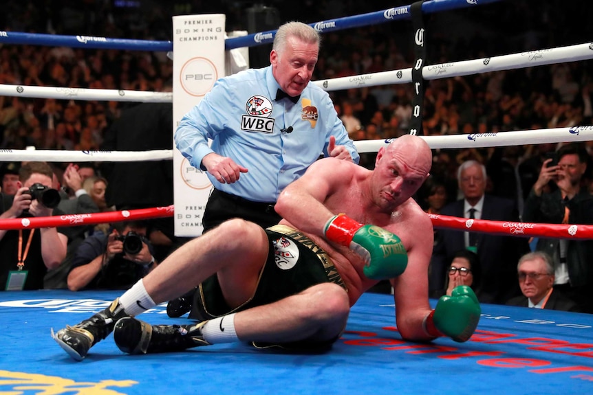 Tyson Fury trying to sit up on the canvas after being knocked down by Deontay Wilder.