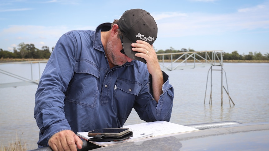 A man in a long-sleeved shirt looks down as he holds his cap.