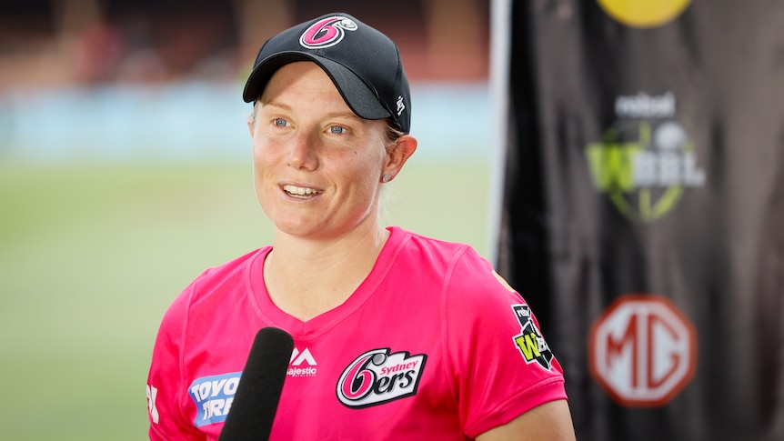 Sydney Sixers cricketer Alyssa Healy stands in front of a microphone during an interview. 