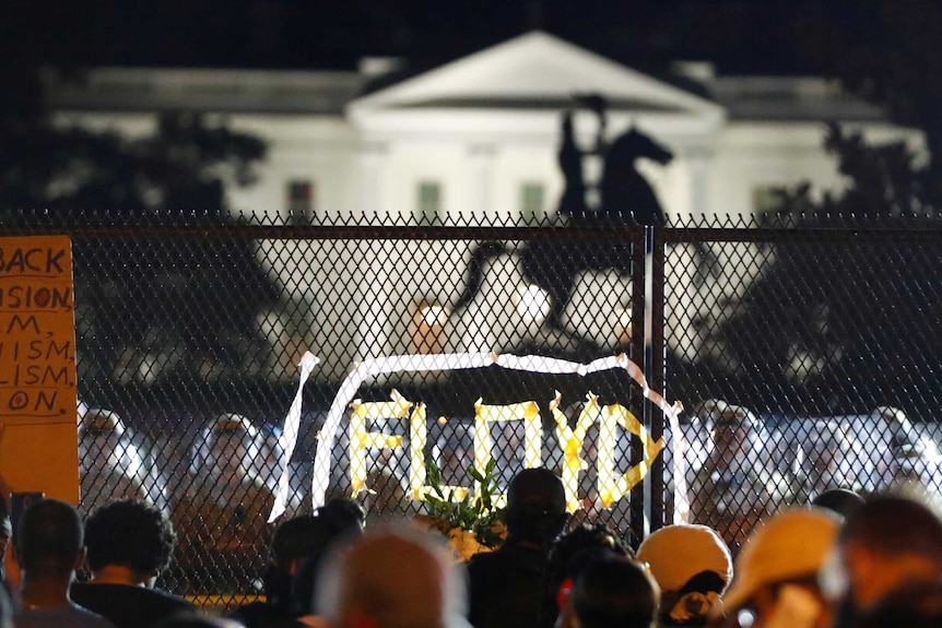 Demonstrators gather along the fence surrounding Lafayette Park outside the White House