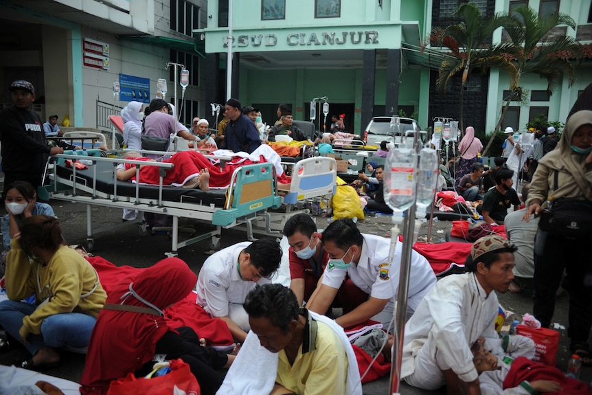 People outside a hospital are treated on the ground and on stretchers. 
