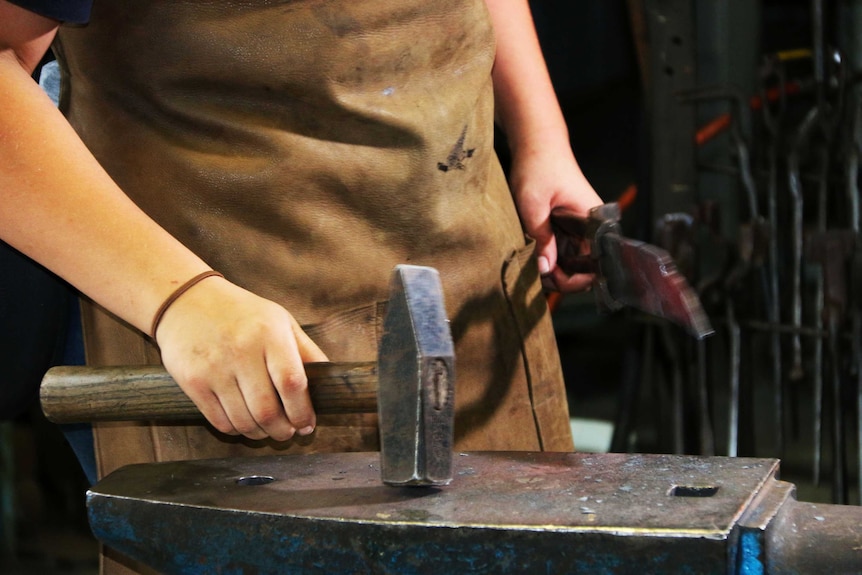 A young woman's hand holding a hammer.