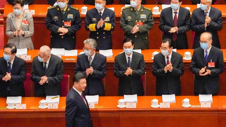 Xi Jinping pasa junto a una fila de delegados chinos enmascarados que aplauden