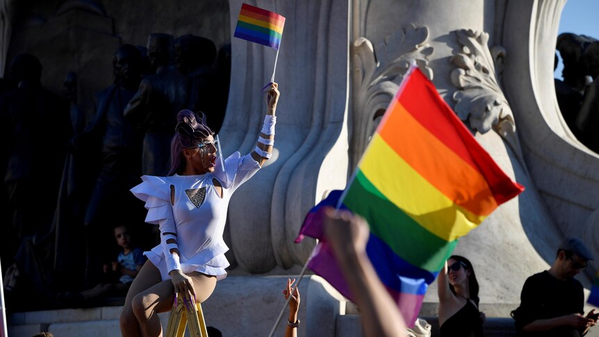 A drag queen holds up a gay pride flag in a crowd of protesters outside parliament in Budapest. 