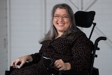 A smiling woman sits in a wheelchair.