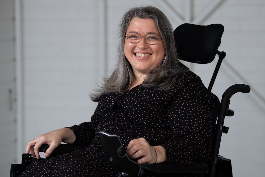 A smiling woman sits in a wheelchair.