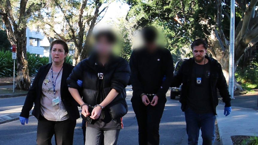 A woman and two men walk along a street.