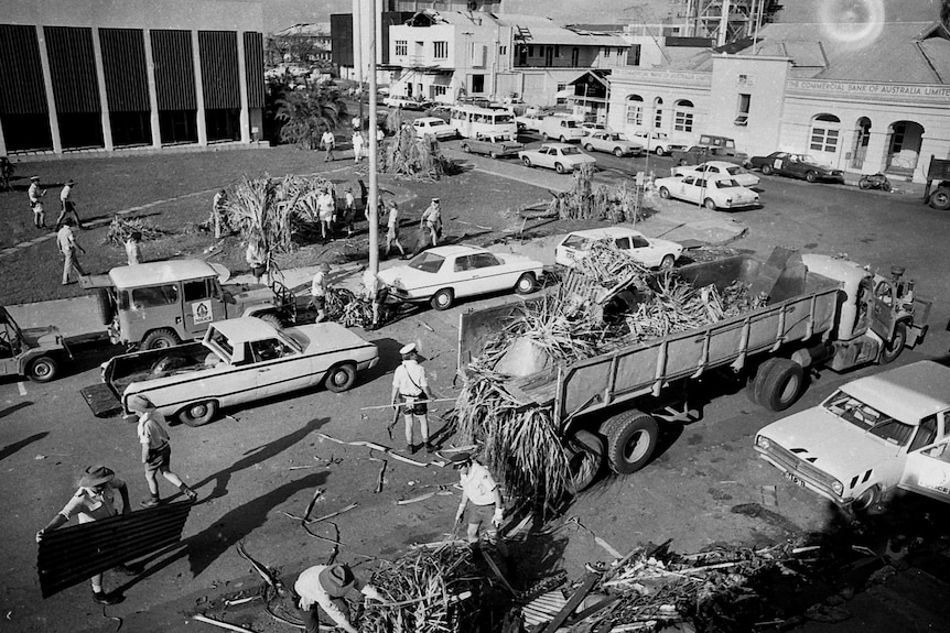 Police and volunteers load piles of wreckage on to the back of a truck in Darwin after Cyclone Tracy