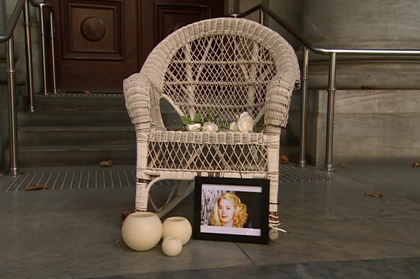 A cane chair with candles, a photo of Ann Marie and flowers on the steps of SA's Parliament House