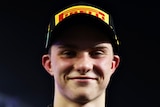 An Australian male Formula 2 driver smiles as he poses for a photo after a race in Saudi Arabia.