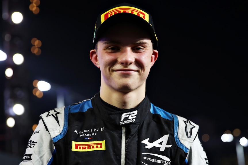 An Australian male Formula 2 driver smiles as he poses for a photo after a race in Saudi Arabia.