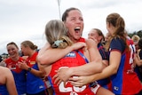 Kate Hore hugs Melbourne Demons teammates and shouts after winning the AFL Women's grand final.