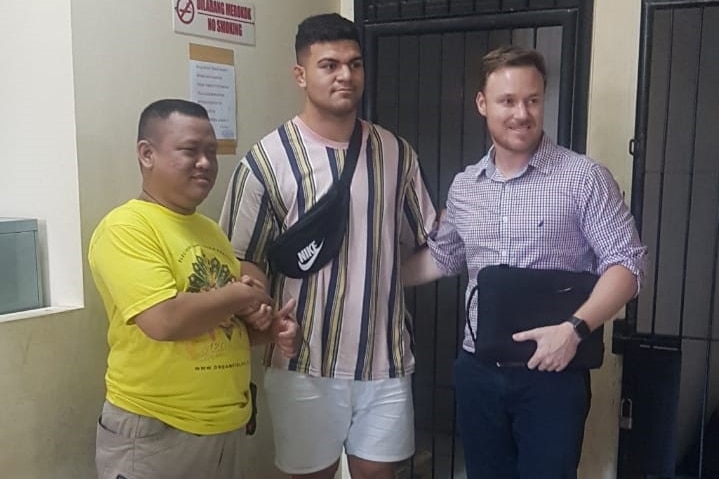 David Fifita, centre, poses for a photo with a man on his left and another on his right outside what appears to be a cell.