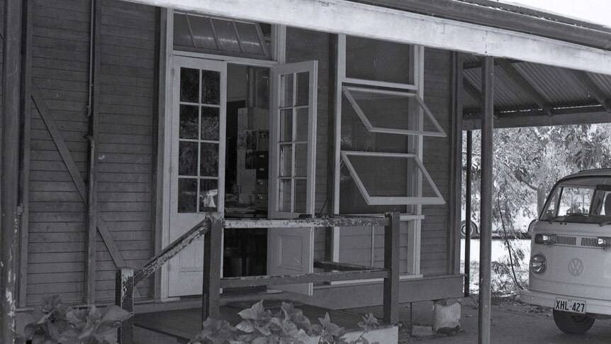 A black and white close-up picture of a classroom building at Broome Primary School, with a Kombi van near the front door.