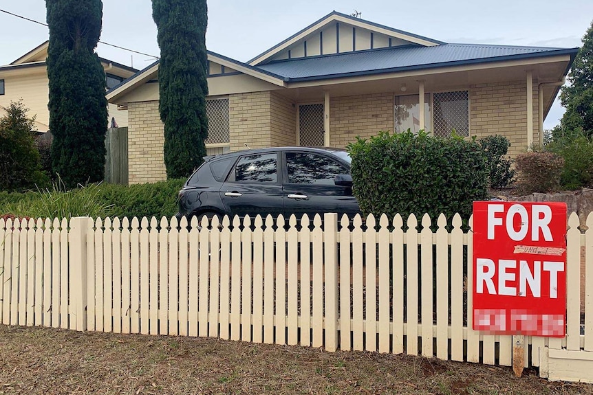 Lowset brick house with For Rent sign out front.