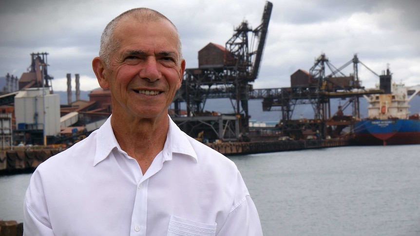 Dom Figliomeni stands at Port Kembla in front of the steelworks.