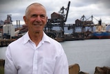 Dom Figliomeni stands at Port Kembla in front of the steelworks.