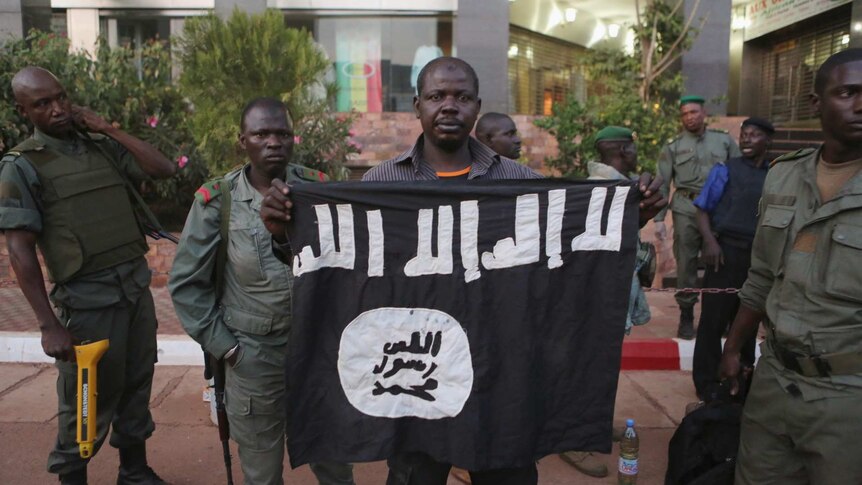 Malian security officials show a jihadist flag they said belonged to attackers in front of the Radisson hotel in Bamako, Mali