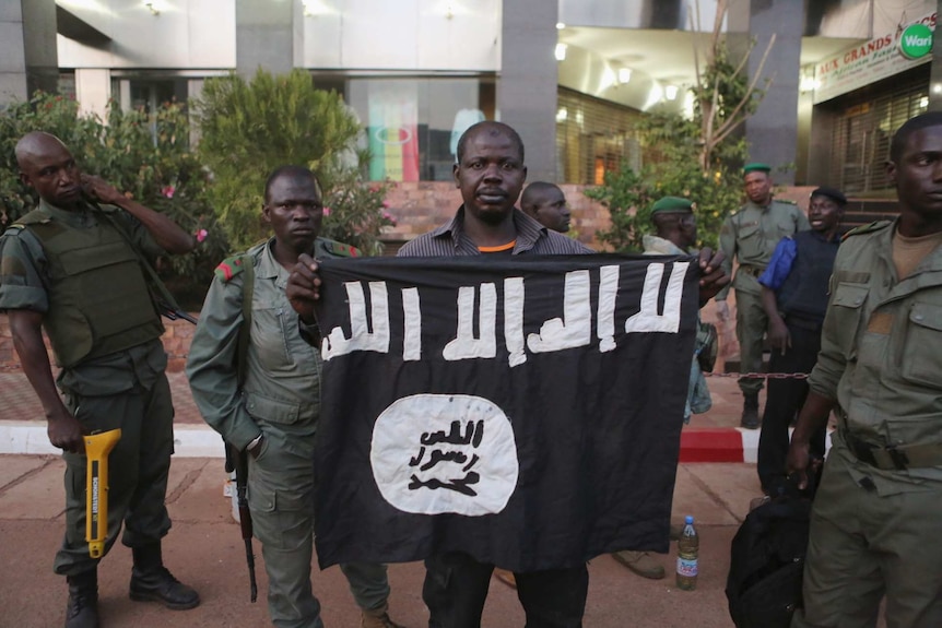 Malian security officials show a jihadist flag they said belonged to attackers in front of the Radisson hotel in Bamako, Mali