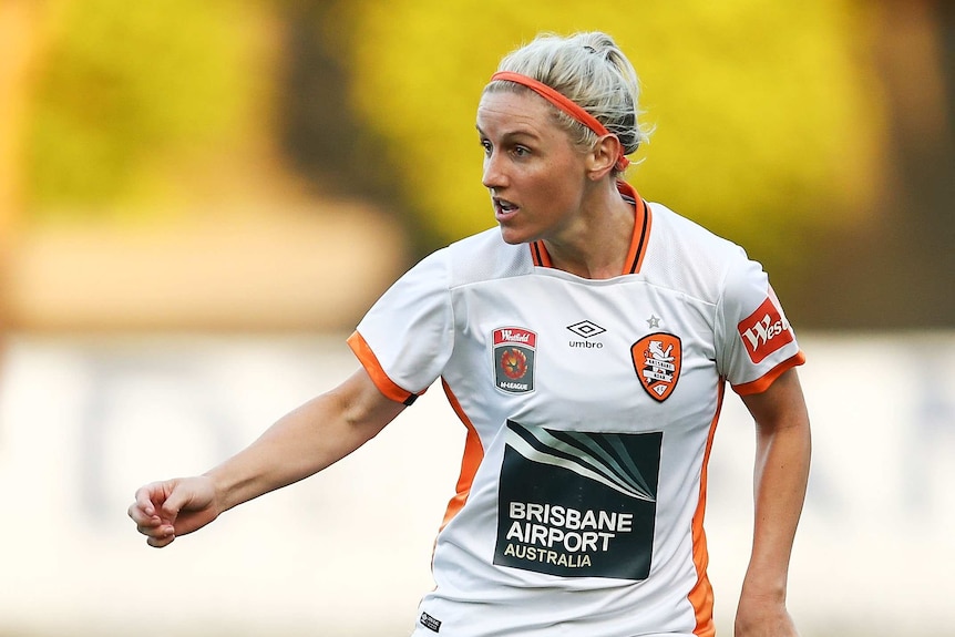 An image of female Matilda football player Amy Chapman playing football in white, orange and black uniform