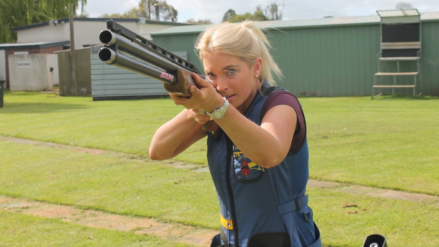 Liz Rymill, SA representative sport shooter stands with rifle at a gun range.