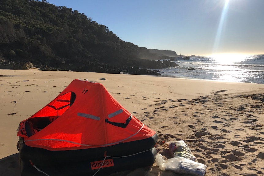 A life raft rests on a beach