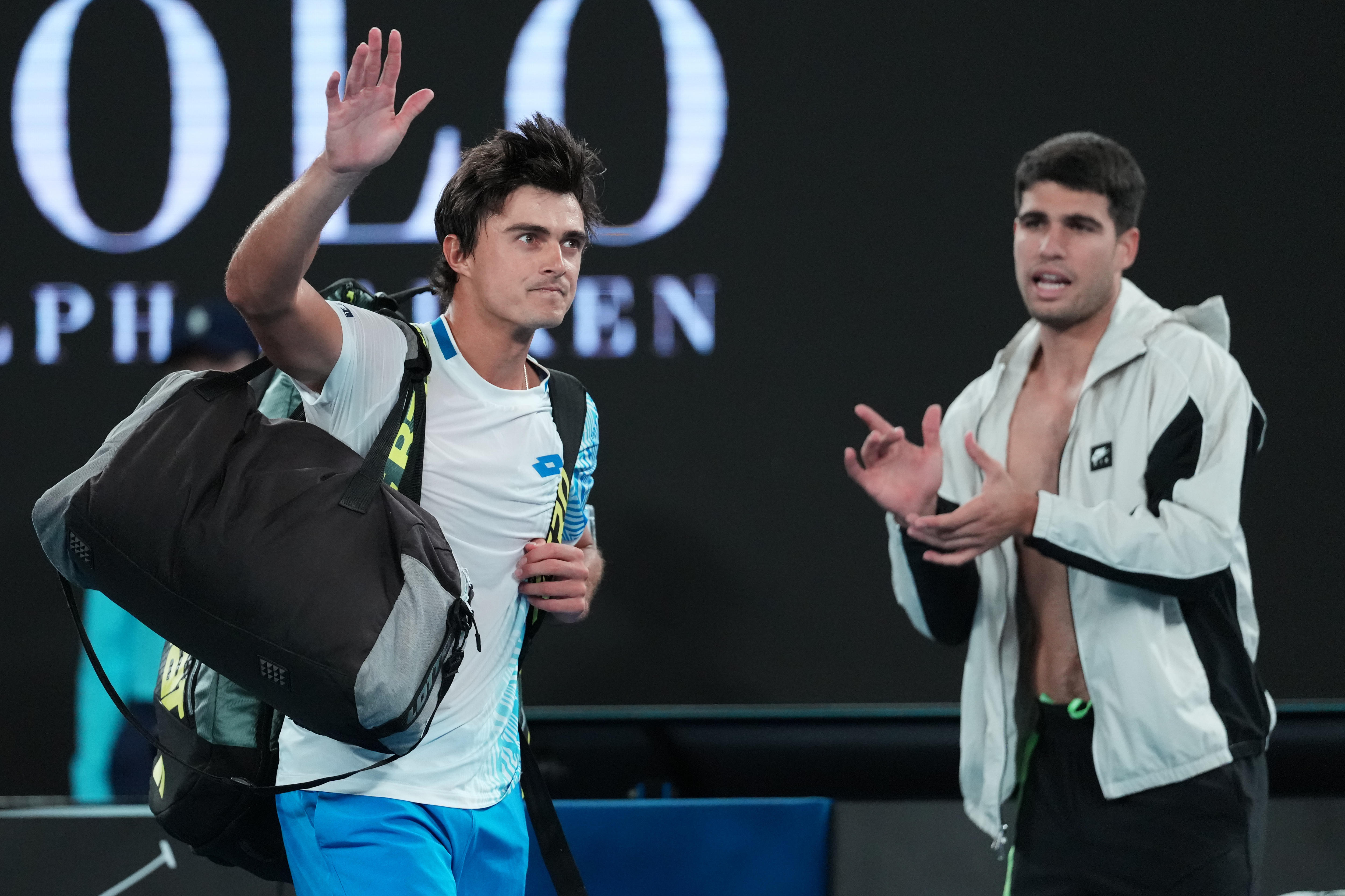 Adam Walton saluda al público del Rod Laver Arena mientras Carlos Alcaraz saluda al fondo.