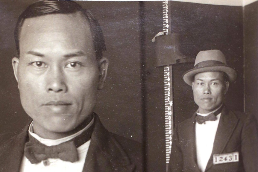 A young Chinese man in a bowtie, suit and hat in a mugshot