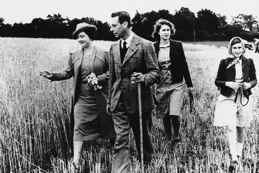 A man and a woman walk through a field with two teen girls 