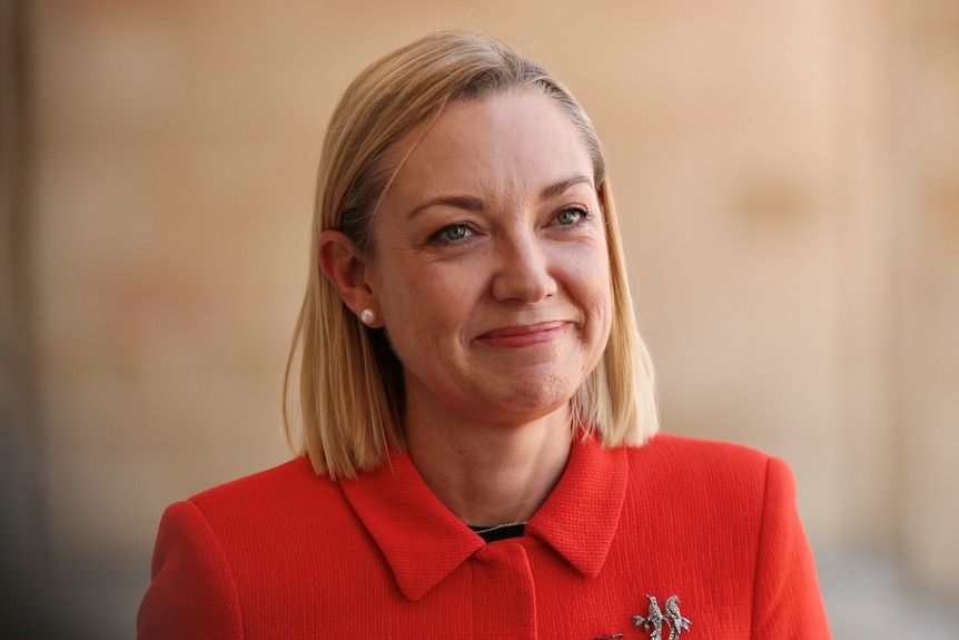 Mia Davies smiles while pictured at parliament house wearing red