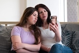 Two women look at a phone