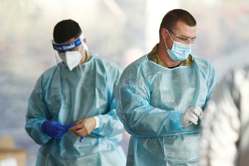 Two men kit up in protective gear to do coronavirus testing