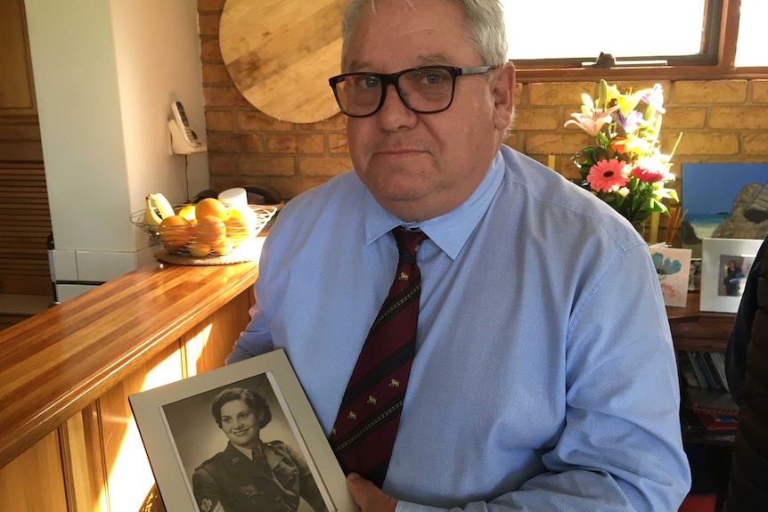 A man holding a wartime picture of a woman