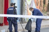 Forensic police examine items including a grey jacket at the Prahran crime scene which is marked off with police tape.