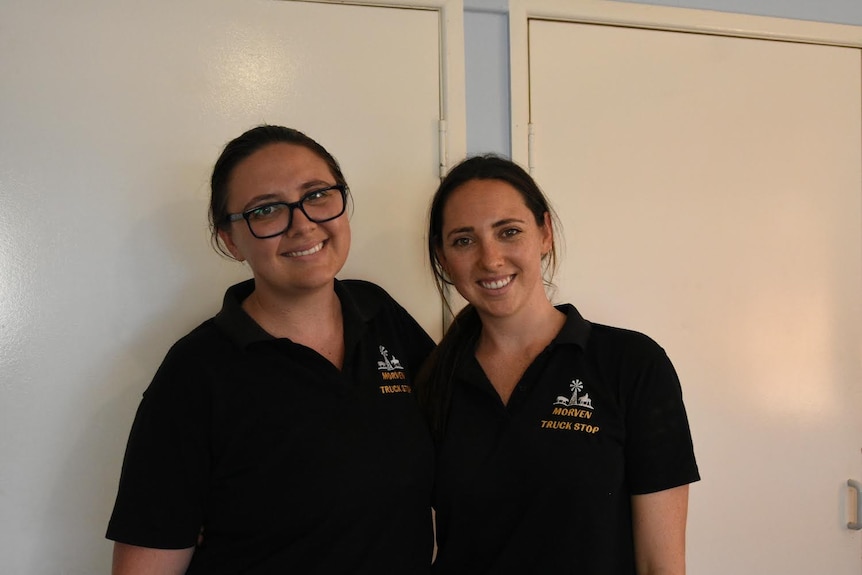 Two women in work attire smiling together