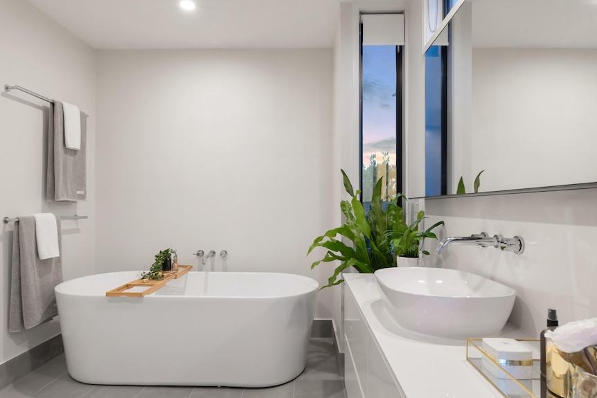 White bathtub in a white-walled bathroom with light grey floor tiles.