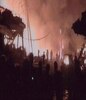 人们在观看炸弹爆炸后建筑物和汽车残骸中熊熊燃烧的大火时看到剪影。