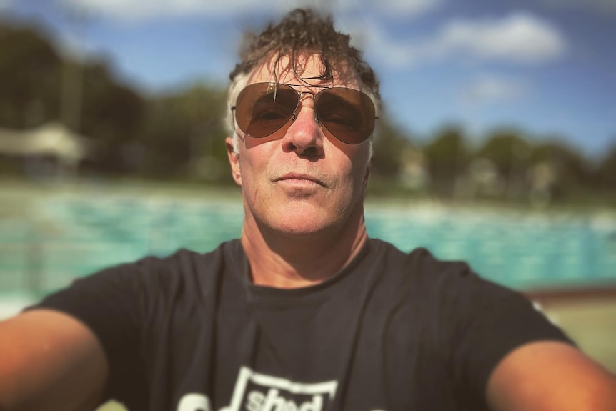 A selfie of middle aged man standing infront of a pool 