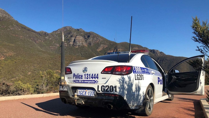 A police car sitting in a car park with Bluff Knoll in the background.